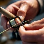 Angler repairing loose fishing rod guide with epoxy and thread wrap