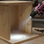 A compact DEKOPRO 8V cordless drill with LED light illuminating a workpiece during a DIY furniture assembly project.