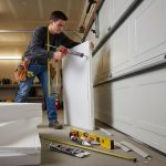 Person installing foam insulation panel inside garage door section using adhesive and measuring tools