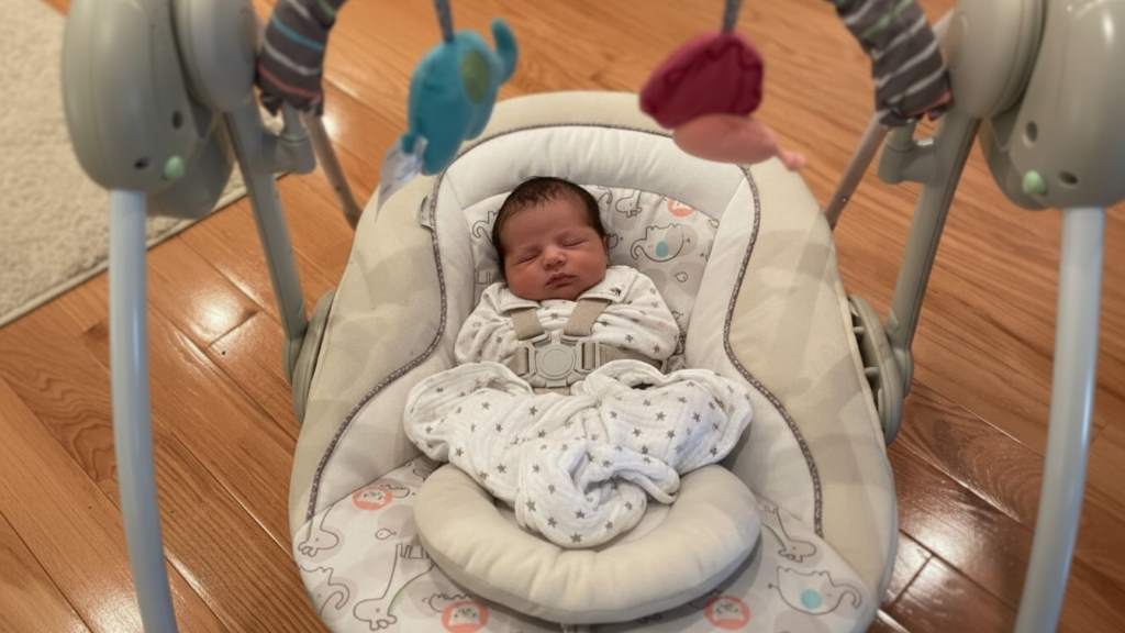 Cozy newborn in padded Ingenuity baby swing with gentle vibration feature