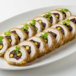 Crystal clear savory aspic coating over sliced chicken galantine with herb garnish on white serving platter