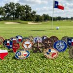 Collection of Texas-themed golf ball markers featuring Lone Star designs and enamel artwork displayed on a putting green