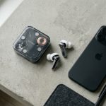 Transparent Nothing earbuds and charging case resting on a minimalist concrete desk.