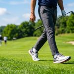 Golfer walking on green fairway grass wearing modern white lightweight golf shoes.
