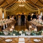 Candlelit reception tables styled with green garlands and elegant hanging fairy lights.